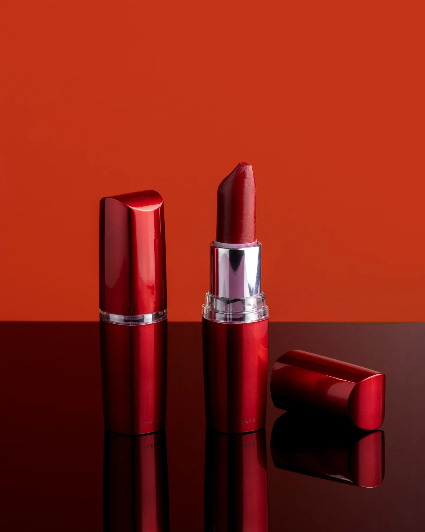 Red lipstick product on a reflective red surface